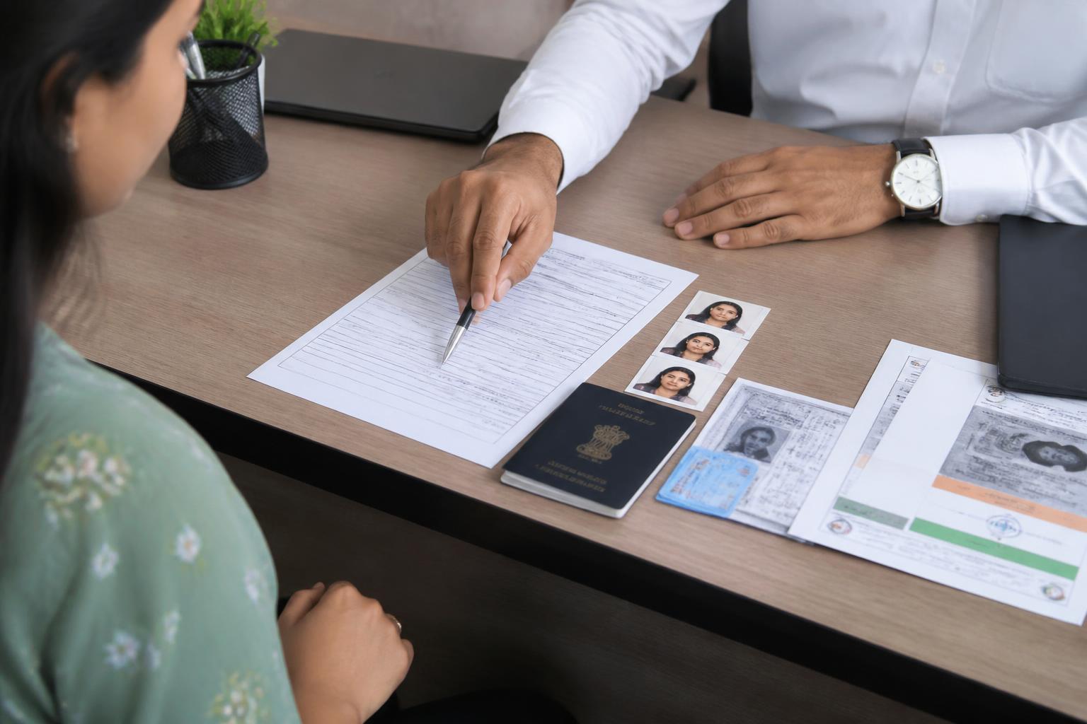 Legal & Document Certification Services — Indian PAN card application form with passport and photographs on a consultant's desk