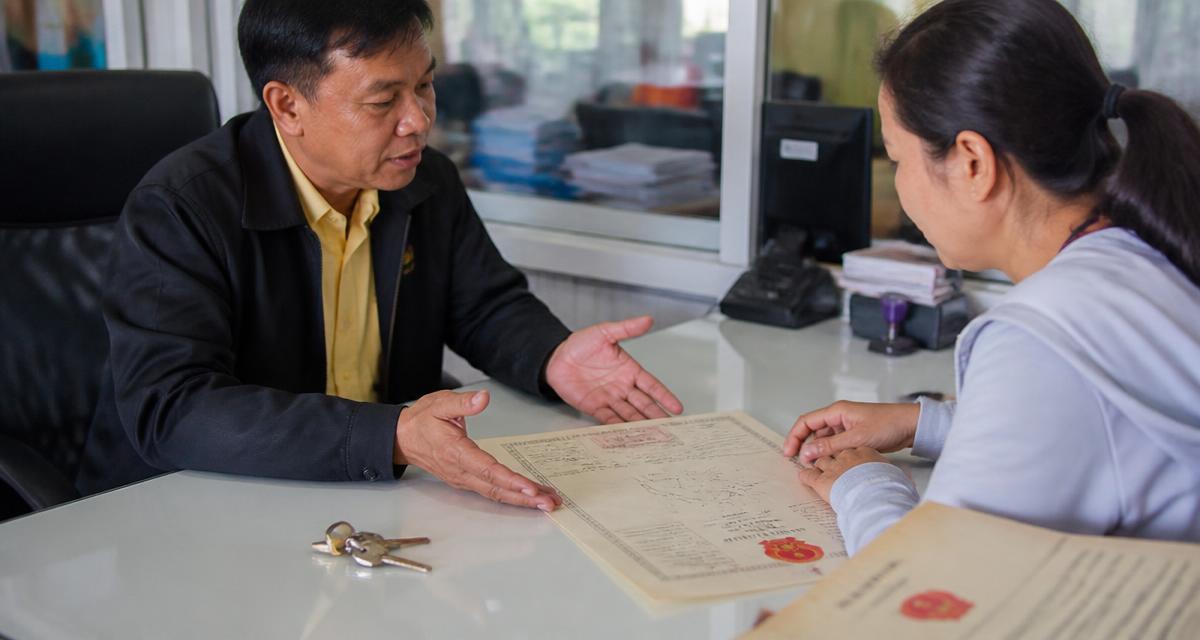 Land office officer explaining a title deed to a buyer